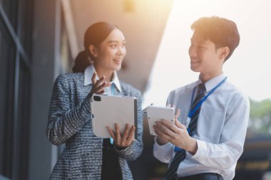 Ofisteki iş arkadaşları ofis binasının dışında yeni projeleri tartışıyor, dijital tablet tutuyorlar. Ofis binalarının önünde duran iki iş arkadaşı iş planını tartışıyor.