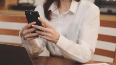 Akıllı telefon üzerinde çalışan ve mesaj yazan genç bir kadın. İş kadını ofiste cep telefonu kullanıyor.