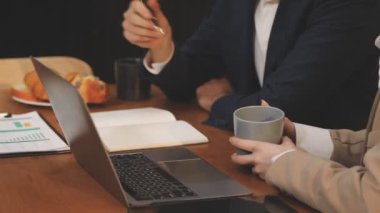 Takım elbiseli iş adamı dizüstü bilgisayar tutuyor ve kahve içiyor.