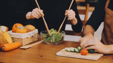 Genç adam ve kadın salata hazırlıyorlar.