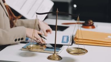Avukat takım elbiseli ve gözlüklü. Masasında belgeler var.