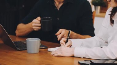 Genç adam ofiste çalışıyor, dizüstü bilgisayar kullanıyor, kahve içiyor..