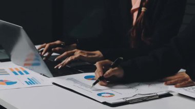 Takım elbiseli iş kadını dizüstü bilgisayar kullanıyor ve notlar yazıyor.