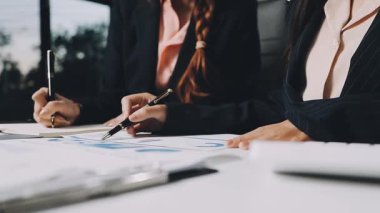 Takım elbiseli ve kravatlı bir iş kadını masada tablet bilgisayarla çalışıyor.