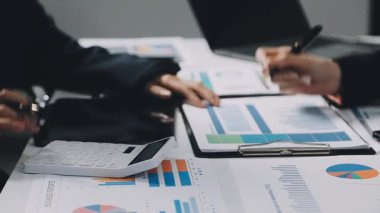 Ekonomik tablolar ve grafikler modern bir ofiste tartışılıyor.