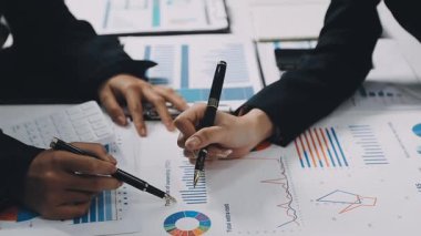 Ofiste dizüstü bilgisayar kullanan ve dosya üzerinde yazan bir iş kadını..