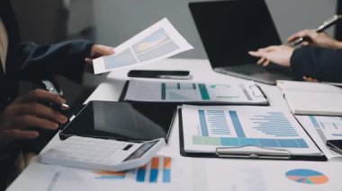 İş adamları masadaki mali tablolar ve grafikleri tartışıyor.