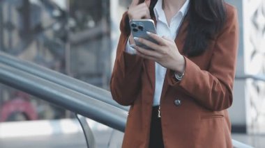 İş kadını akıllı telefon kullanarak sokakta yürüyor.