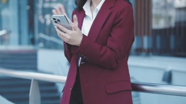 Genç Asyalı iş kadını ofiste cep telefonu kullanıyor.