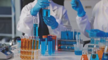 Koruyucu eldivenli bilim adamı deney tüplü matarayı tutuyor.