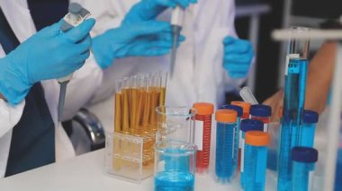 Bilim adamı elinde sıvı test tüpleri tutuyor.