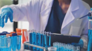 Bilim adamı elinde bir test tüpü tutuyor.