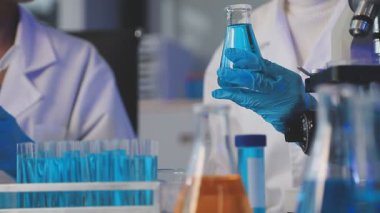 Laboratuvarda test tüplerini sıvı ile tutan bilim adamlarının yakın çekimi..