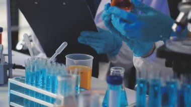 Test tüpüyle çalışan koruyucu eldivenler içinde laboratuvar asistanı..