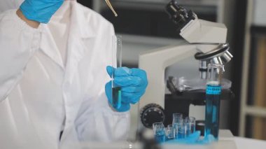 Bilim adamı deney tüpüyle cam tutuyor.
