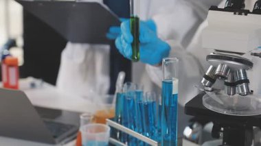 Koruyucu kıyafetli laboratuvar asistanının elinde kan olan test tüpünü kapatın.