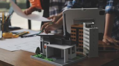 Emlakçı ev modeli ve model ev planları gösteriyor.