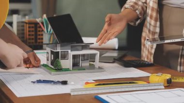 Ev modeline sahip mühendis ya da mimar kadın, ofisteki inşaatın planını ve planını çiziyor. İnşaat ve mühendislik tasarımı kavramı, mühendislik