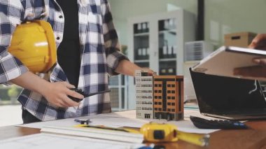 Genç Asyalı kadın mühendis planla evde çalışıyor.