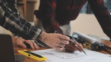 Planı olan ve masada çalışan genç bir mimar.