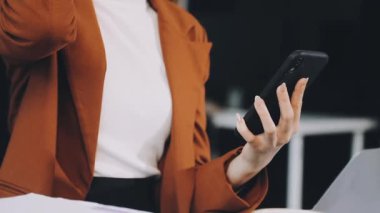 Ofisteki masada cep telefonu olan genç bir kadın..