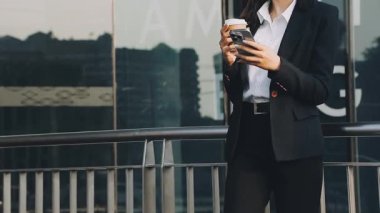 Genç iş kadını şehirde otururken akıllı telefon kullanıyor.