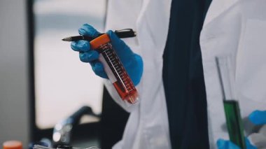 Koruyucu eldivenli bilim adamı laboratuvar analizi için bir tüp tutuyor..