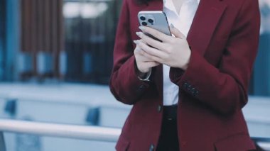 Takım elbiseli genç bir iş kadını cep telefonu kullanıyor.