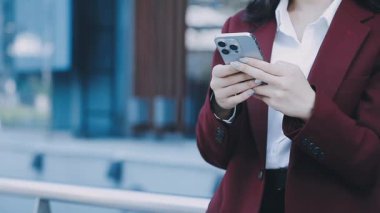 Takım elbiseli kadın elinde akıllı telefon tutuyor..