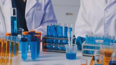 Laboratuvarda mikroskopla koruyucu eldivenler ve test tüpleriyle bilim insanlarını kapatın.