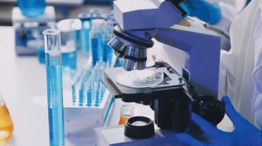 Mavi eldivenli laboratuvar asistanı laboratuarda pipetli test tüpü tutuyor. tıbbi araştırma, bilim ve teknoloji konsepti.