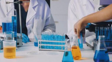 Bir matara ve test tüpleriyle laboratuvar asistanı..