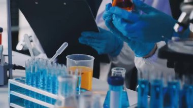 Modern bir laboratuvarda mikroskopla çalışan koruyucu gözlüklü bir laboratuar bilimcisi.