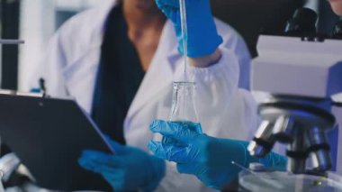 Bilim adamı laboratuarda test tüpleriyle tablet kullanıyor.