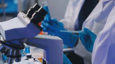 Laboratuvar araştırması. Laboratuvarda deney tüpleriyle çalışan bir bilim adamı. Bilimsel araştırma, biyomühendislik ve mikroskop.