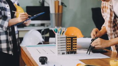 Mimar, planlarla birlikte ofiste planlar üzerinde çalışıyor..