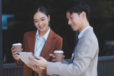 Başarılı genç iş adamları modern iş binası önünde konuşuyor, birlikte çalışıyorlar.