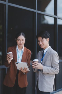 Başarılı genç iş adamları modern iş binası önünde konuşuyor, birlikte çalışıyorlar.