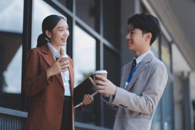 Başarılı genç iş adamları modern iş binası önünde konuşuyor, birlikte çalışıyorlar.