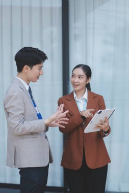 Başarılı genç iş adamları modern iş binası önünde konuşuyor, birlikte çalışıyorlar.