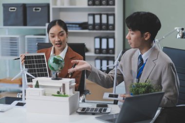 kadın alternatif enerji mühendisi bir yel değirmeni güç örnek model tutun ve stüdyoda alternatif güç kaynağı için onun erkek arkadaşı ile tartışmak