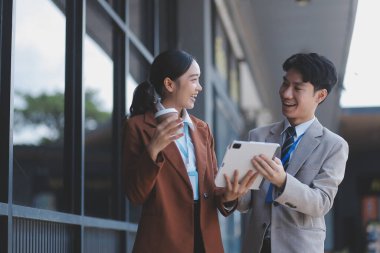 Başarılı genç iş adamları modern iş binası önünde konuşuyor, birlikte çalışıyorlar.