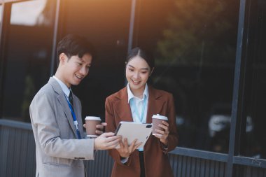 Başarılı genç iş adamları modern iş binası önünde konuşuyor, birlikte çalışıyorlar.