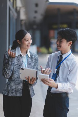 Ofisteki iş arkadaşları ofis binasının dışında yeni projeleri tartışıyor, dijital tablet tutuyorlar. Ofis binalarının önünde duran iki iş arkadaşı iş planını tartışıyor.