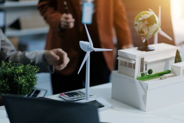 kadın alternatif enerji mühendisi bir yel değirmeni güç örnek model tutun ve stüdyoda alternatif güç kaynağı için onun erkek arkadaşı ile tartışmak