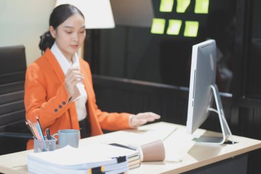 Genç ve sevimli Asyalı iş kadını gece boyunca iş belgeleriyle çalışıyor, gece fazla mesai yapıyor..