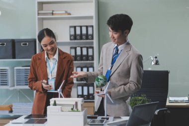 kadın alternatif enerji mühendisi bir yel değirmeni güç örnek model tutun ve stüdyoda alternatif güç kaynağı için onun erkek arkadaşı ile tartışmak