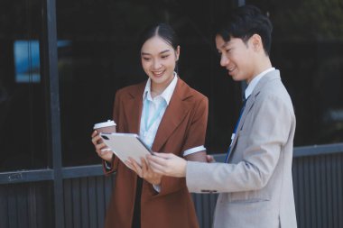 Başarılı genç iş adamları modern iş binası önünde konuşuyor, birlikte çalışıyorlar.