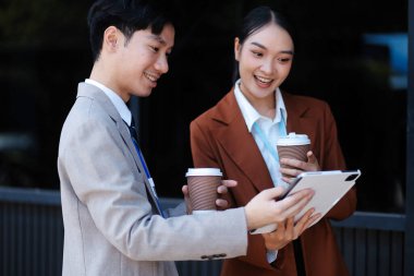 Başarılı genç iş adamları modern iş binası önünde konuşuyor, birlikte çalışıyorlar.