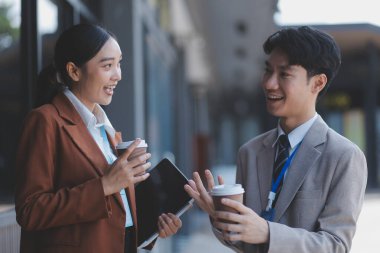 Başarılı genç iş adamları modern iş binası önünde konuşuyor, birlikte çalışıyorlar.